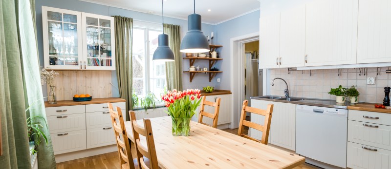 header of a kitchen with green curtains and table with orange taulips in a vase